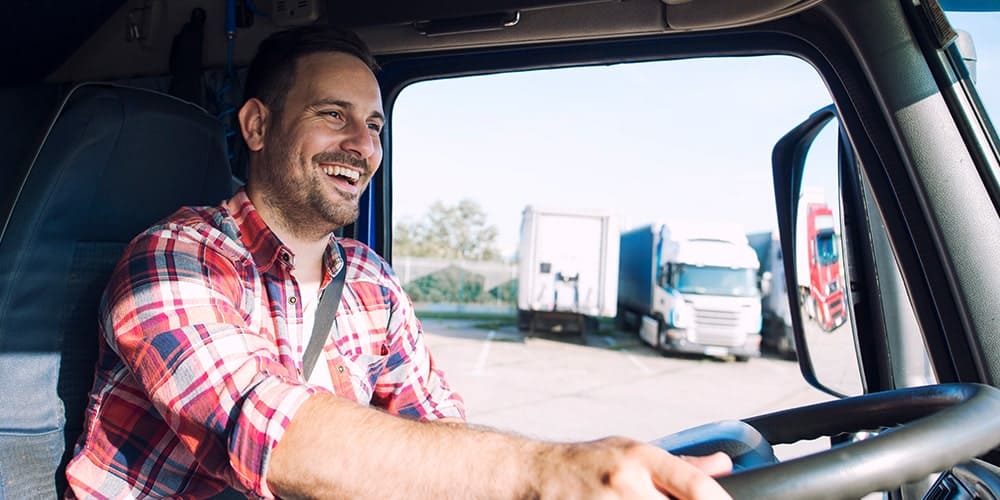 homem-de-camisa-xadrez-dirigindo-seu-caminhão-feliz