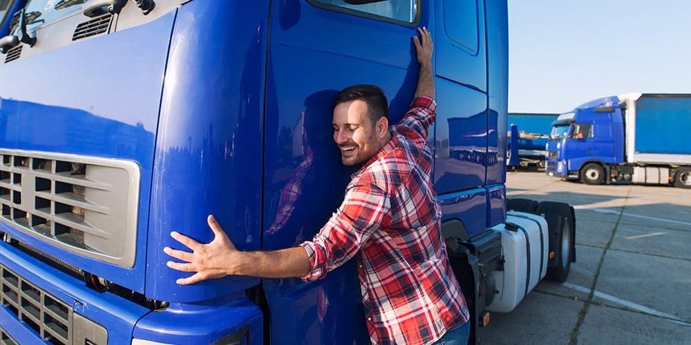 homem-de-camisa-xadrez-abraçando-caminhão-azul
