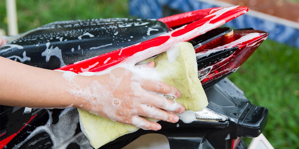 motocicleta-vermelha-sendo-limpa-com-bucha-e-sabão